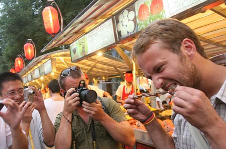 Photo: Tourists try Chinese snacks at Donghuamen night fair in Beijing