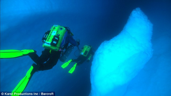 在南极洲潜水时，潜水队员在海面下与巨大的冰山面对面