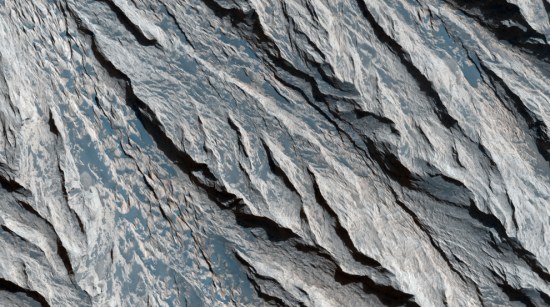 堪德峡谷(Candor Chasma)里暴露在外的岩层和矿物。此图显示了水手谷(Valles Marineris)的浅色分层沉积物上的悬岩。很多岩层的边缘因大风侵蚀而留下V型图案。