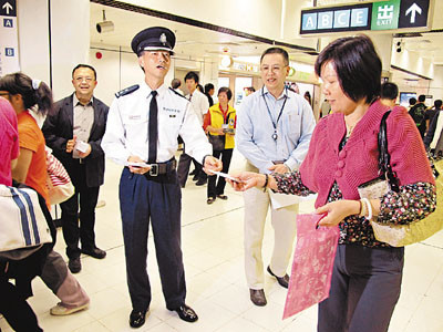香港警方铁路警区指挥官郑国鸿与23名灭罪耆英派发宣传物品,提醒