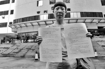 走出法庭后，李君给记者展示她此前告赢沃尔玛的判决书。摄/记者刘畅