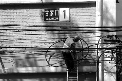 甘家口1号楼,一名工作人员在拆除电线杆后重新接电源供电。 北京海淀区甘家口三栋老楼改头换面(组图)