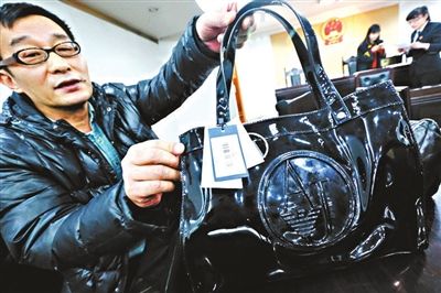 张先生展示材质不合格的阿玛尼包(图片来源：北京青年报)