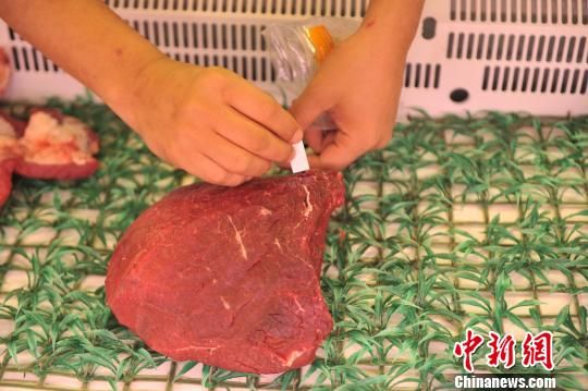 渝北区食药监局工作人员在生鲜柜台牛肉区，用快速测试纸测试牛肉水分。 陈超 摄