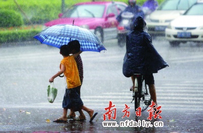 共撑一把大伞的两个小男孩带着刚买的青菜冒雨回家.本报记者梁宇摄