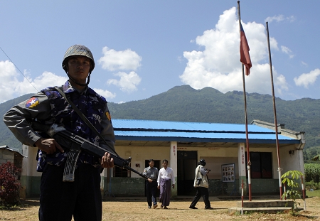 9月8日,一位缅甸士兵正在果敢特区首府老街持枪站岗,他身后是一些