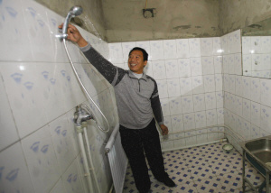 12月11日，黑心工厂老板李兴林在展示厂里德淋浴设备，而记者调查得知“包身工”两年间从未洗过澡。