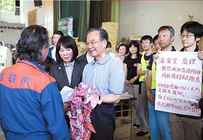 温家宝在日本名取市馆腰小学体育馆灾民避难所慰问受灾民众，向名取市市长佐佐木赠送中国汶川地震灾区的小朋友折的千纸鹤。新华社发
