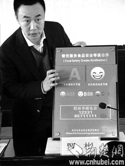 武汉市食品药品监督管理局副局长罗彬展示“样板牌”。