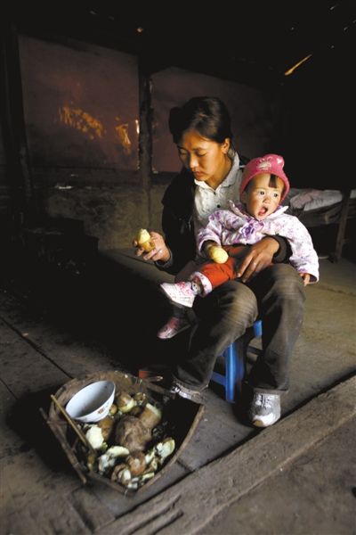 云南省高寒村，1岁半的小云香在妈妈怀中吃土豆。