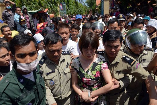 当地时间10月22日，柬埔寨逾千人在金边王宫游行，抗议一家柬埔寨服装厂的一位中国籍女性管理员由于员工“怠工”，撕毁柬前国王西哈努克画像。图为警方将该中国籍女子带去画像前道歉。来源：中国警察网