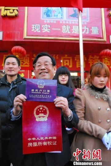 谷殿明展示为雷锋办理的"户口本","房产证". 熊堰秋 摄