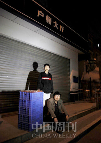 4月16日，卖了一天草莓的张建党带着儿子在北京某派出所户籍大厅前接受拍照， 警察的到来最终让拍摄不得不终止。记者匆忙摁了一下快门， 失焦的画面看起来像许多非京籍考生的未来。中国周刊记者／商华鸽 摄 