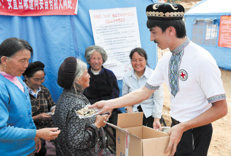 8月7日"切糕王子"阿迪力在鲁甸县龙头山镇向地震受灾群众发放切糕.