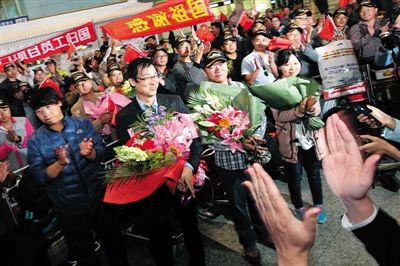 昨晚9时许，首都机场三号航站楼，首批从也门撤离的104名归国人员在航站楼到达区内挥舞国旗。本版摄影/新京报记者 李飞