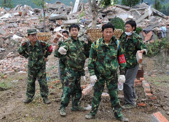 图文:几名民兵预备役人员在废墟中搬运砖块