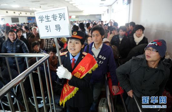 1月12日,南昌火车站一名工作人员手举指示牌引导学生进站上车.