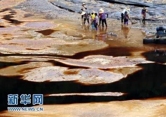 资料图：工人在清理发生渗漏的紫金矿业铜矿湿法厂污水池内剩余的污水（2010年7月13日摄）。新华社记者 姜克红 摄