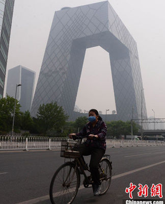 图为5月7日中午，市民戴口罩从央视大楼前经过。