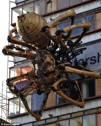 一栋高楼外侧窗户上悬挂一只巨型机器蜘蛛