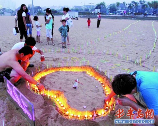 青岛小伙浪漫求爱 沙滩上用蜡烛为女友摆 心