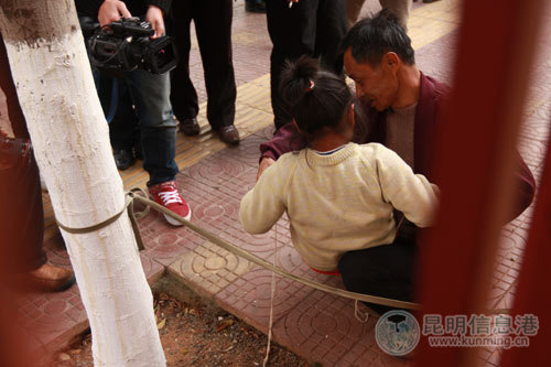 在市民要求下，女孩的父亲给她解开绳子，而女孩就会不断的打自己的脸。记者朱仁严/摄