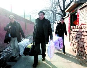 昨日，52岁的菜贩范国梁（中）在老乡的帮助下置办新的生活用具到出租房内，本报记者 郭铁流 摄