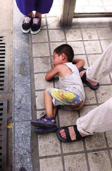 小孩被抱到路边，一开始很抵触陌生人，最后在地上睡着了。图/网友“高尚的秦超