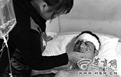 吕某躺在病床上，妻子用药水为他清洁面部伤口 本报记者 张杰 摄 