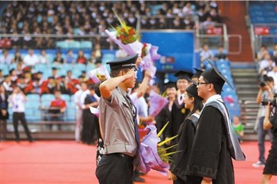 毕业生代表为学校教师、教务人员、保安送花致谢，一名保安回礼。京华时报记者 王海欣 摄