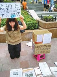 重庆朝天门，陈得娟在街头跪地卖拥抱，希望为孩子筹款治病。