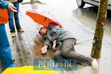 2名女孩为雨中横卧街头醉汉撑伞(图)