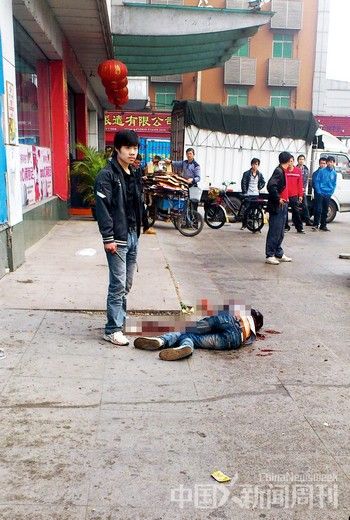 2月14日,东莞厚街车站凶案现场,吴刚(左)持匕首站在受伤倒地的舒照岭