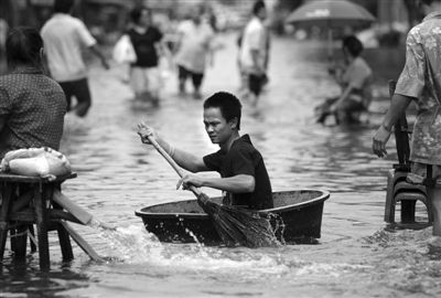 28日，泰国首都曼谷，灾民在被洪灾淹没的街道中划行。泰国总理英拉27日要求曼谷市民尽量离开曼谷，以避免人员发生危险。