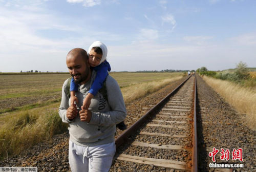 匈牙利边境城市的地中渡一条火车轨上，一个叙利亚难民父亲背着自己的海难孩子沿着火车铁轨行走。