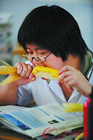 一名高三备考生,一边看书,一边大口地吃着玉米,仿佛恨不得将书中的内容也一并吞下。 一名高三备考生,一边看书,一边大口地吃着玉米,仿佛恨不得将书中的内容也一并吞下。
