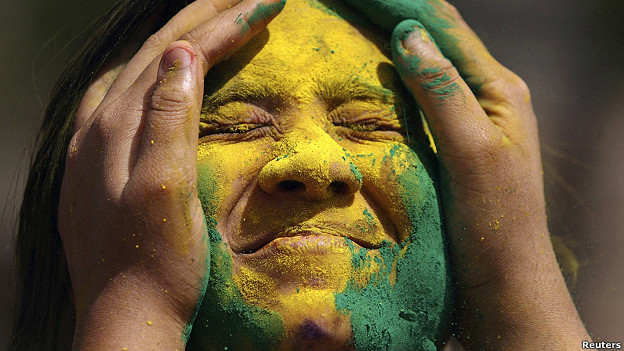 An Indian woman has coloured powder put on her face