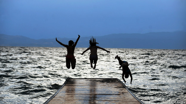 Three girls jump in the Ohrid Lake in Macedonia at sunset