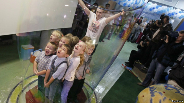A giant bubble is formed around a group of children.