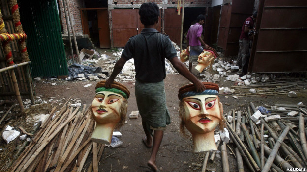 A man carries polystyrene heads to form part of a platform being built for the Durga Puja festival.