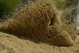 图片说明：大力击球，泼起大片沙子