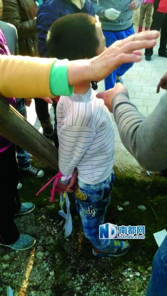 同伴菜地里偷西红柿,结果7岁的男孩小聪被菜农反绑在木桩上.