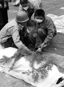 15日,绵竹,救援人员正安慰一位在地震中失去孩子的母亲 新华社 图为