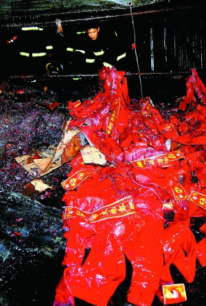 1月27日,消防人员在事故现场清理未燃的鞭炮.