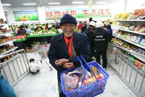 某社区生鲜超市开业时,一位老人买了不少便宜货 资料图片