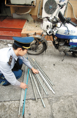 该小区保安向记者展示打人者遗留在现场的14根铁棍和一辆摩托车.