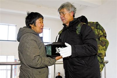 赵俊方将骨灰盒交给李贵友的妹妹李桂花. 新文化报 白石 摄