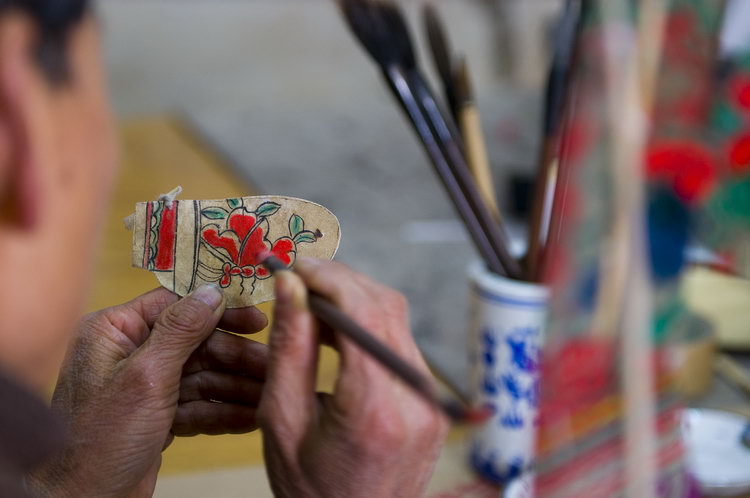 图文:孙先生正在仔细绘制皮影