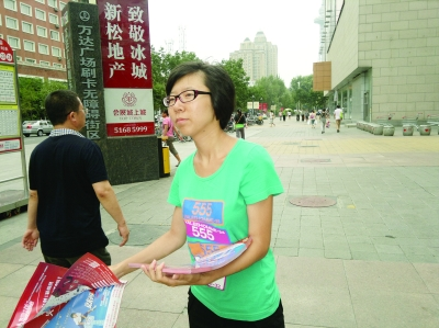 记者见到了李莹,她正站在超市出口,手捧着厚厚一沓传单,一张一张递给