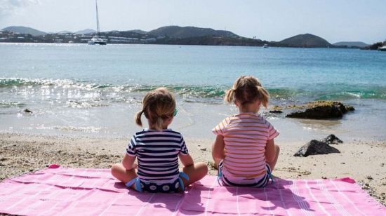 两个女儿坐在沙滩上萌萌哒。
